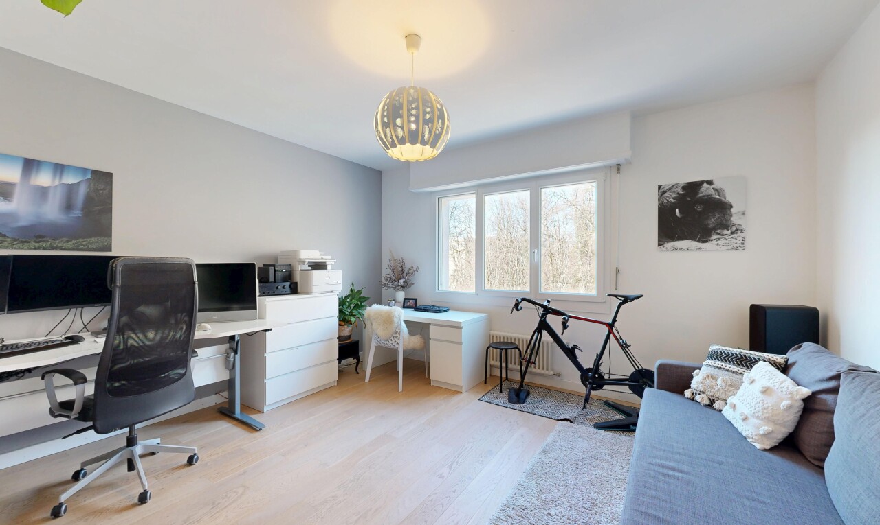 büro mit bürobereich, fernseher, wood finish floor, holzfußboden, und drywall
