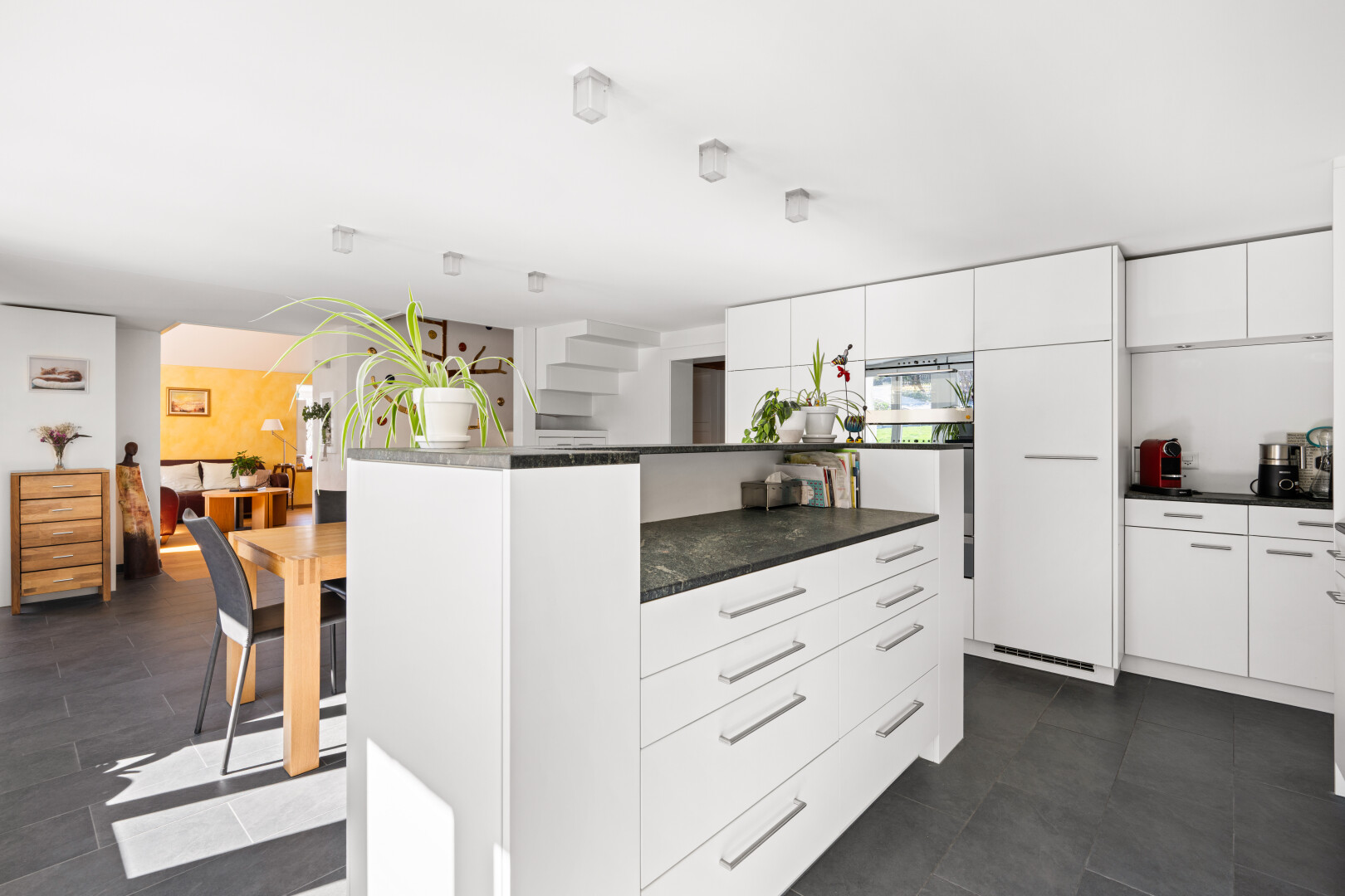 cuisine avec two heights countertops, dark floor, kitchen island, îlot de cuisine, et white cabinets