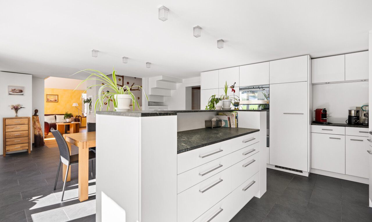 cuisine avec two heights countertops, dark floor, kitchen island, îlot de cuisine, et white cabinets