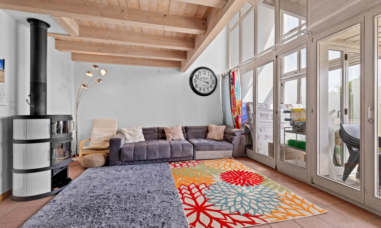 tiled living area with a wooden ceiling with exposed beams and a wood stove