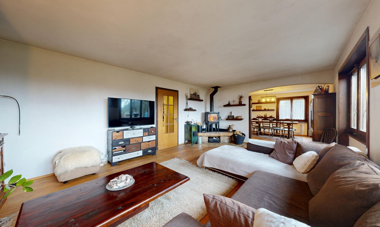 salon avec poêle à bois, télévision, cloison sèche, drywall, et inside property