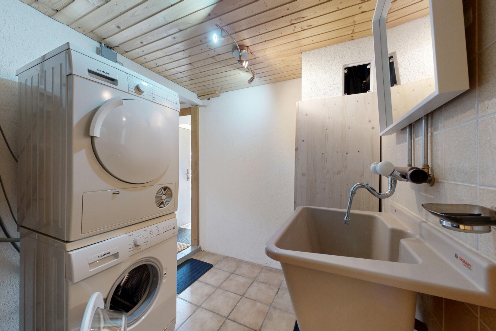 buanderie avec inside property, light floor, plafond en bois, wood ceiling, et lave-linge et sèche-linge superposés