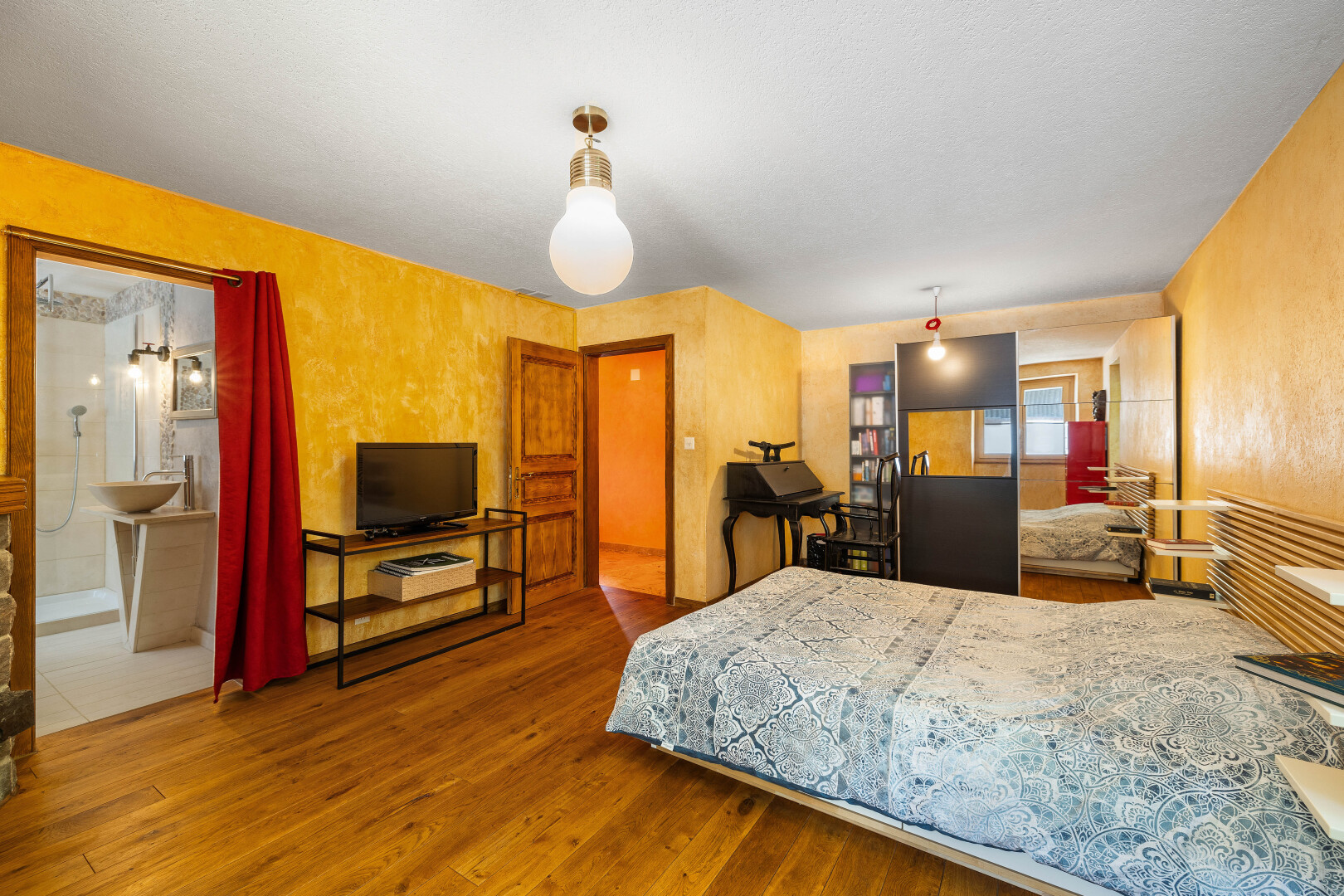 chambre avec télévision, sol en finition bois, wood finish floor, inside property, et lumière naturelle