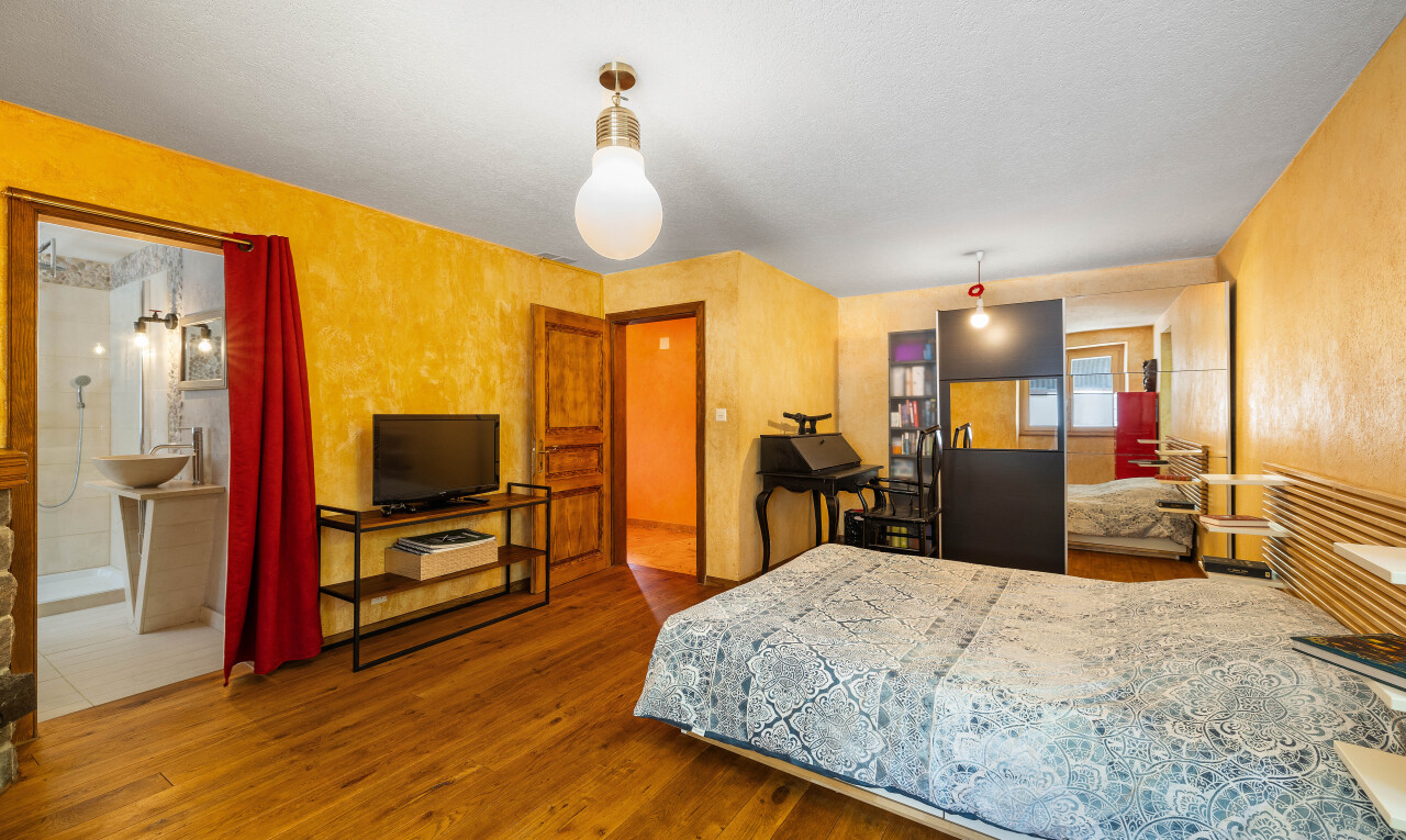 chambre avec télévision, sol en finition bois, wood finish floor, inside property, et lumière naturelle