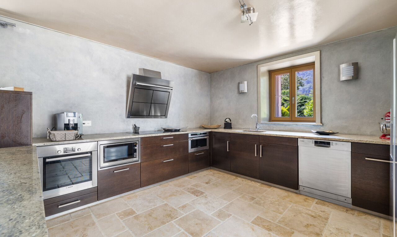 cuisine avec four, lave-vaisselle, micro-ondes, plans de travail, et stone finish floor