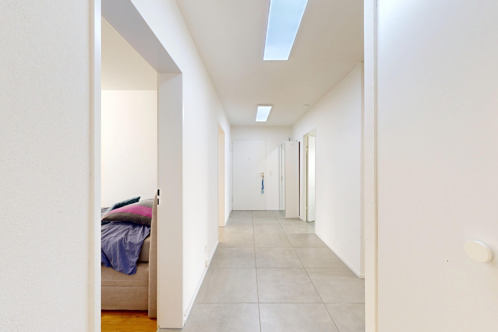couloir avec inside property, puits de lumière, drywall, cloison sèche, et tile floor