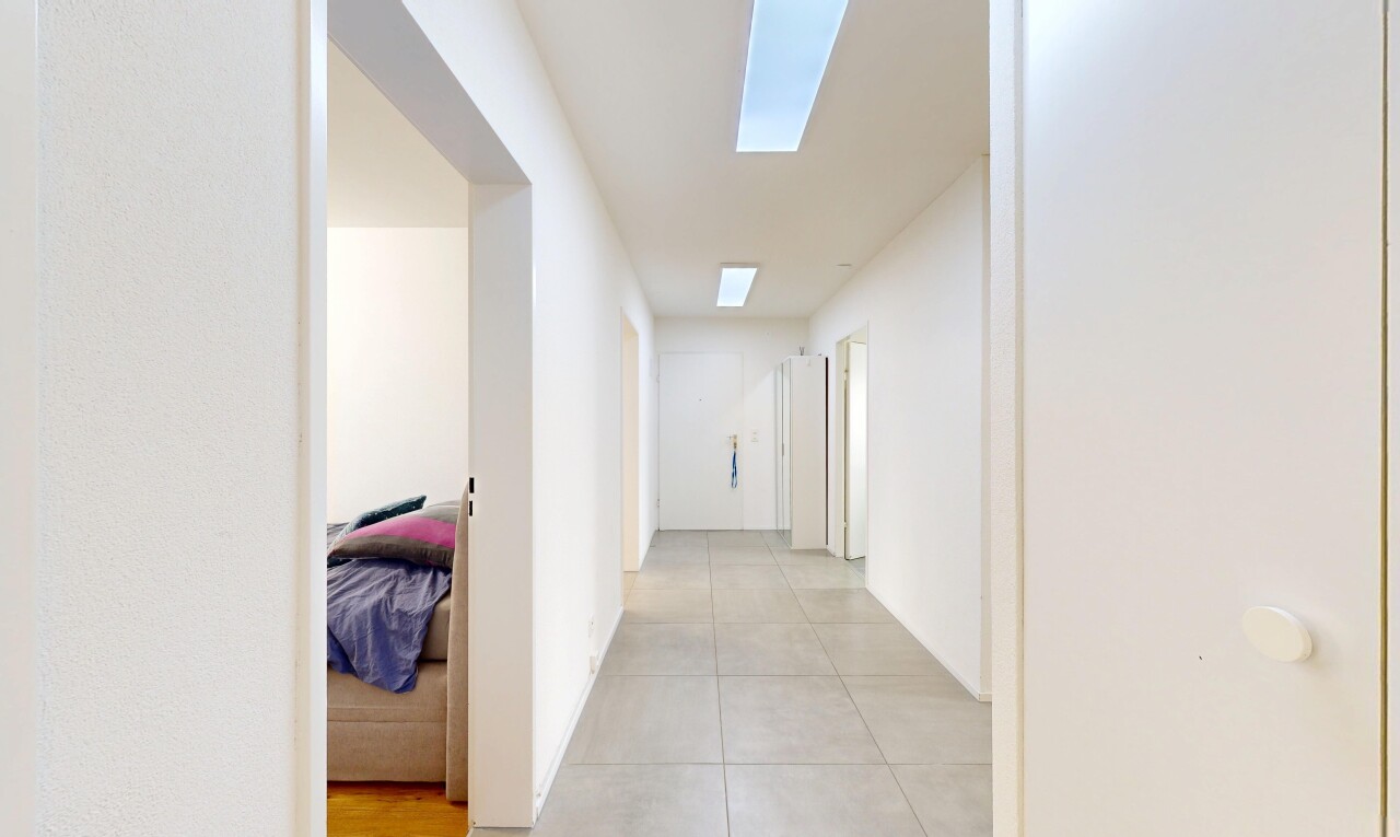 couloir avec inside property, puits de lumière, drywall, cloison sèche, et tile floor