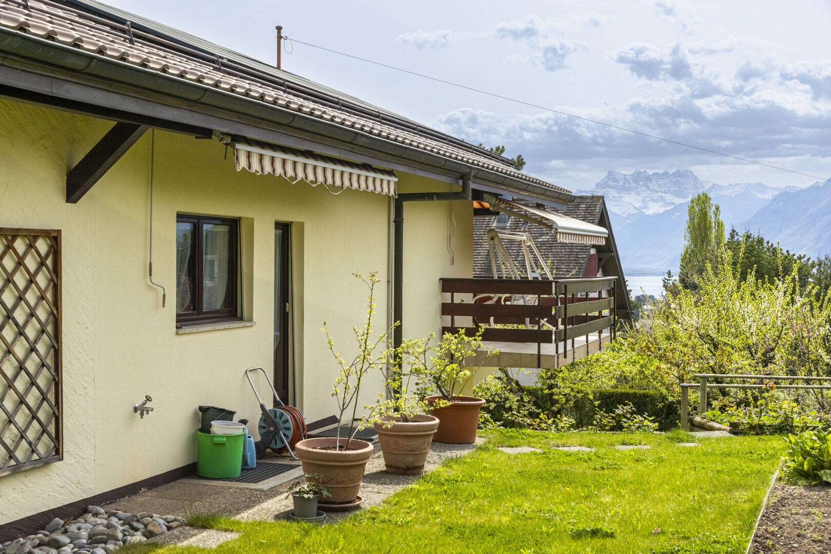 façade avec bardage en stuc, auvent, from property, pelouse, et vue sur la montagne