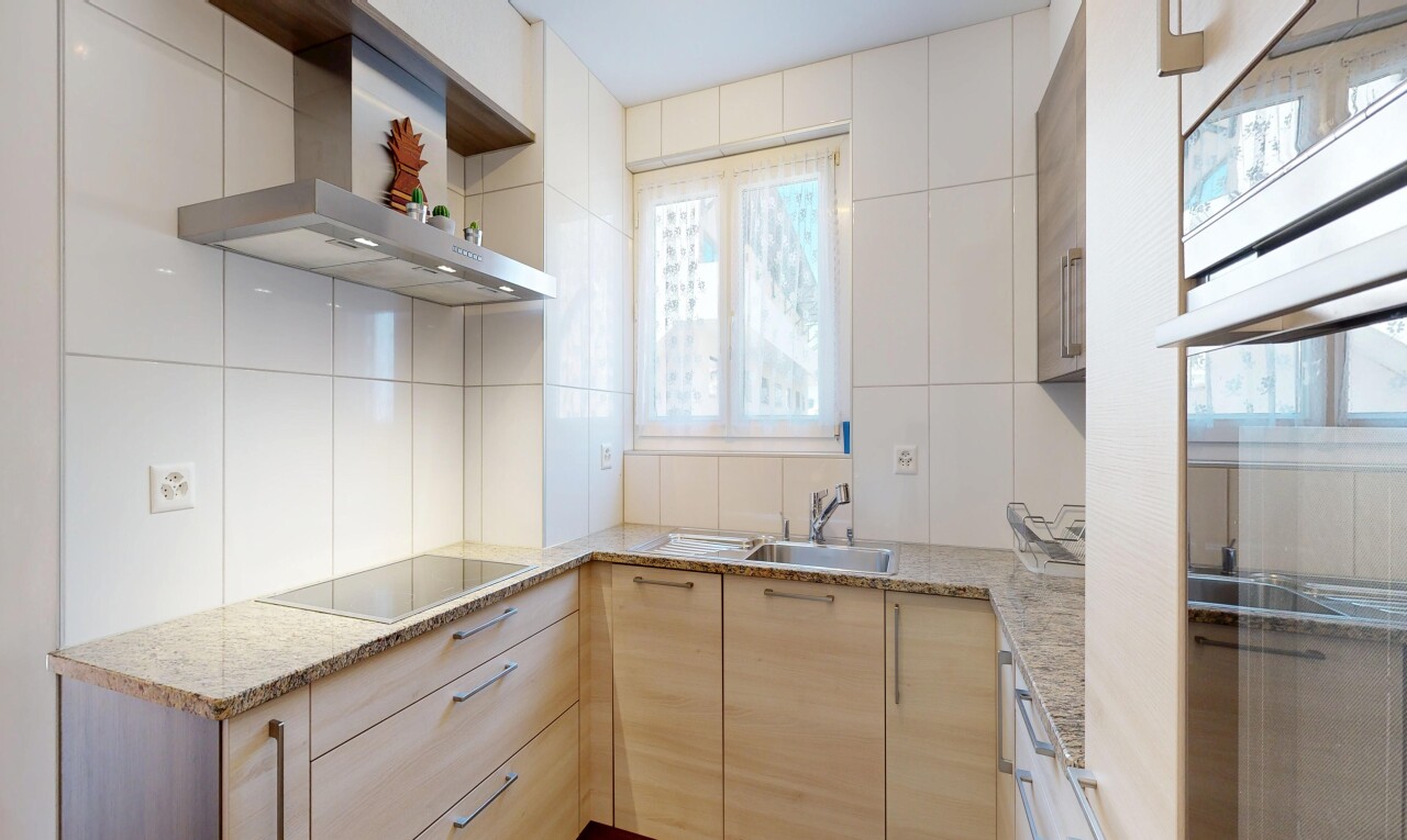 cuisine avec hotte, plans de travail en pierre, stone countertops, armoires marron clair, et light brown cabinets