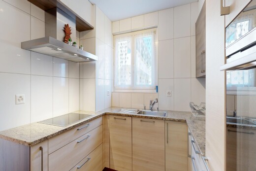 cuisine avec hotte, plans de travail en pierre, stone countertops, armoires marron clair, et light brown cabinets