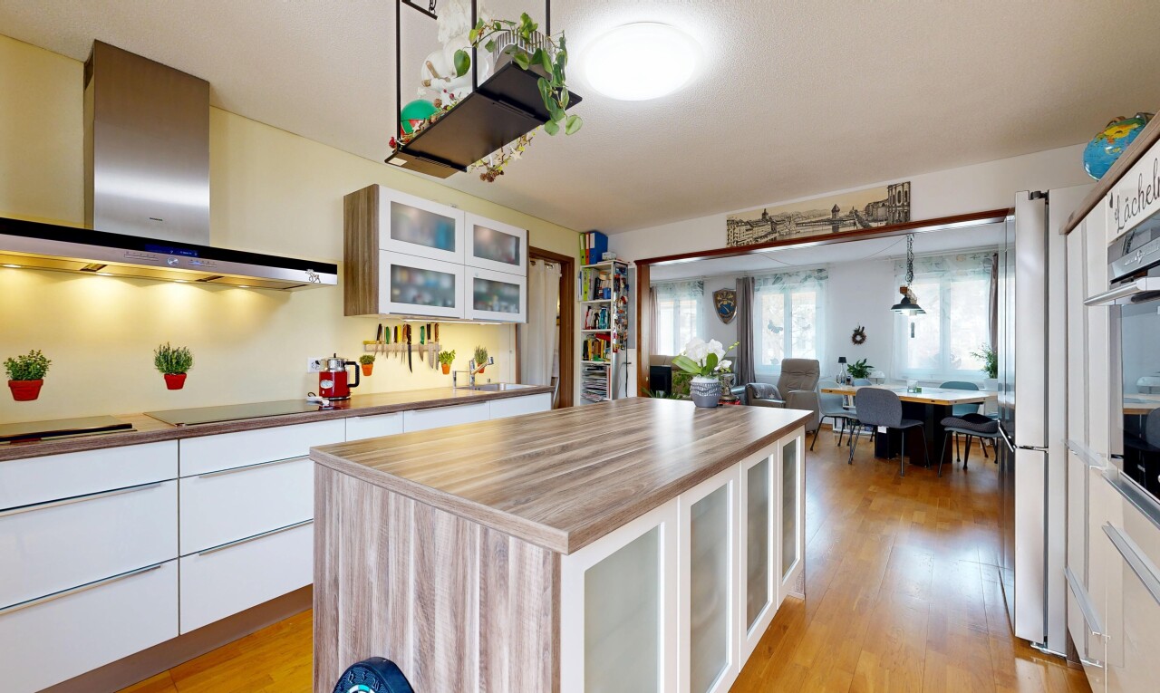 cuisine avec armoires avec insert en verre, armoires blanches, hotte, sol en finition bois, et wood finish floor