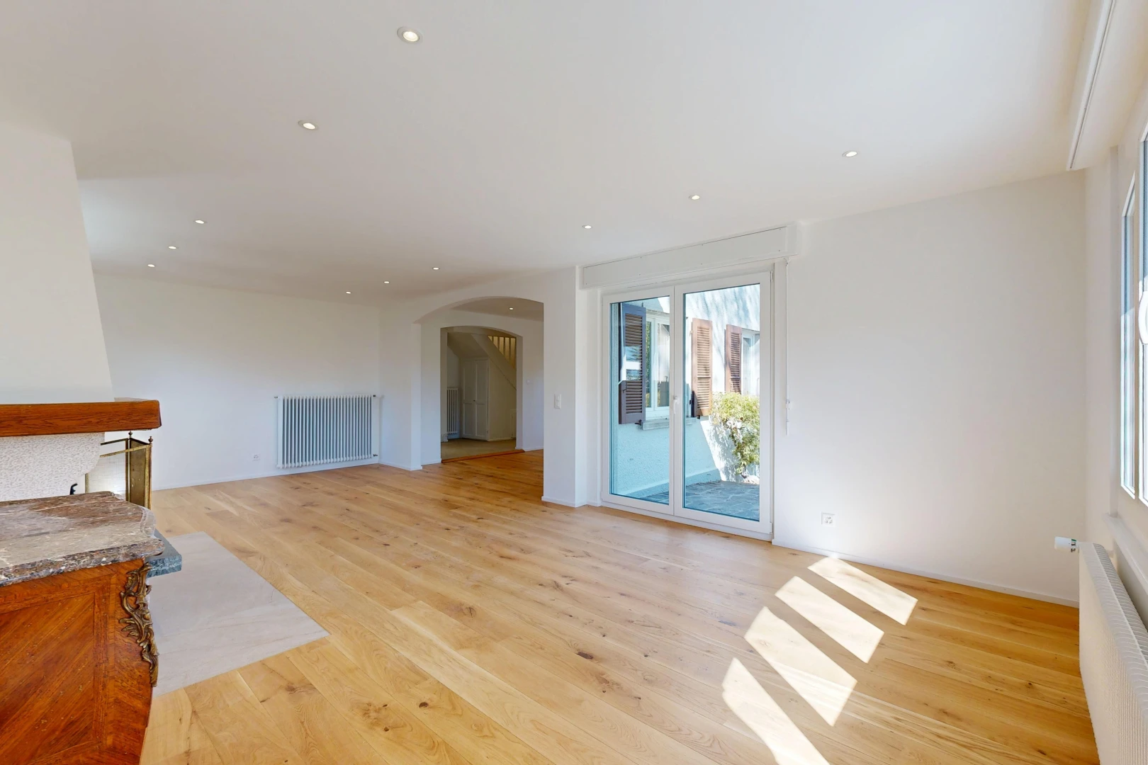 pièce vide avec passages en arc, radiateur, éclairage encastré, drywall, et cloison sèche