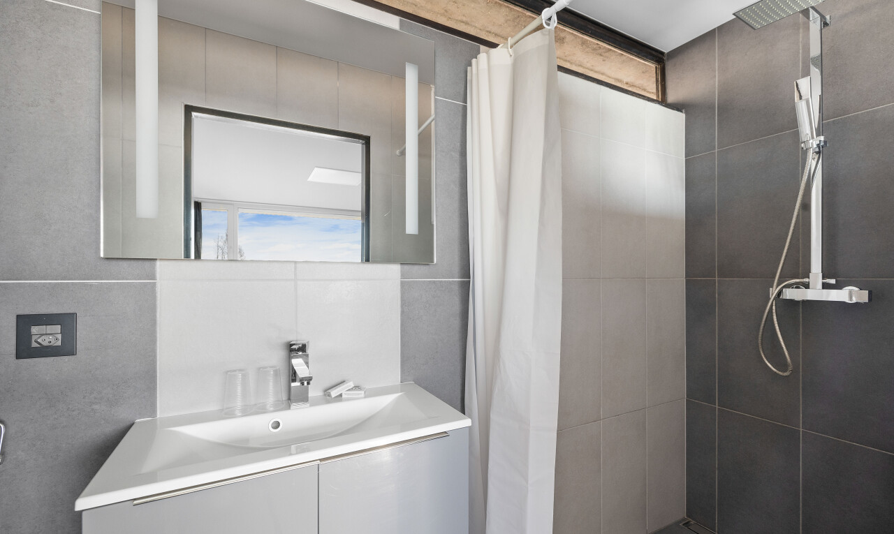 salle de bains avec lavabo (ou coiffeuse selon le contexte), évier, miroir, douche, et salle de bain complète