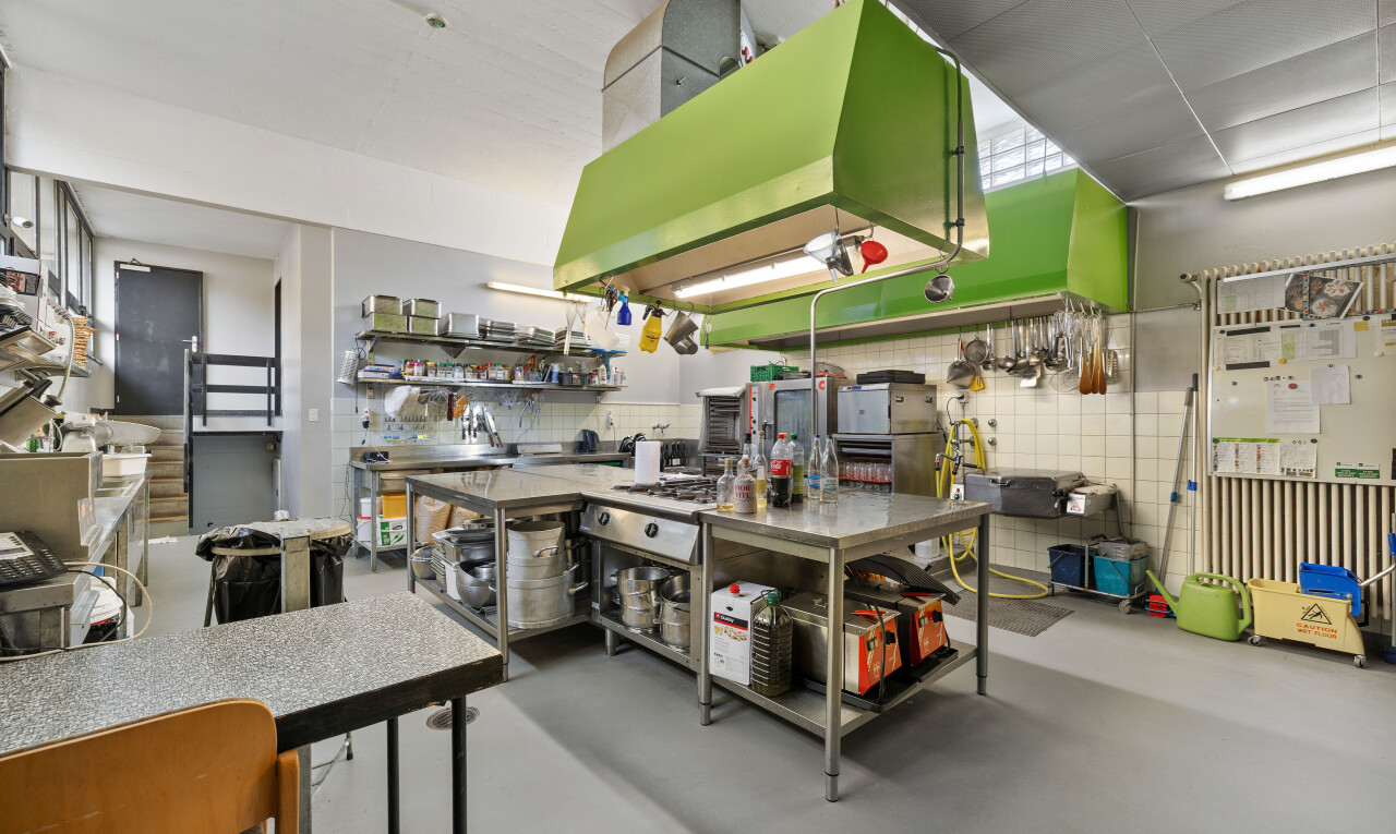 cuisine avec mur en carrelage, sol en béton, hotte, et cloison sèche