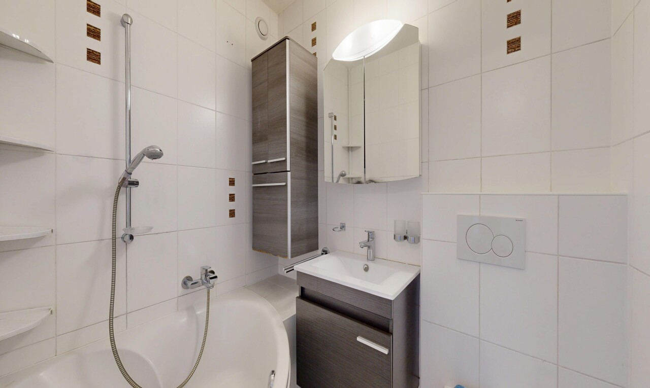 full bath featuring tile walls, vanity, and tub / shower combination