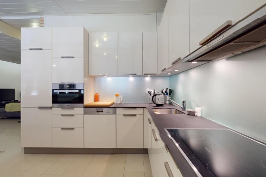 küche mit herd, fernseher, weiße schränke, ofen, und waschbecken