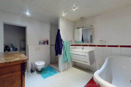salle de bains avec meuble-lavabo, miroir, toilettes, et mur carrelé