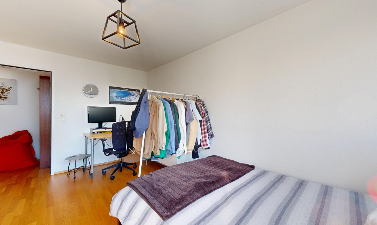 chambre avec espace bureau, drywall, cloison sèche, télévision, et wood finish floor
