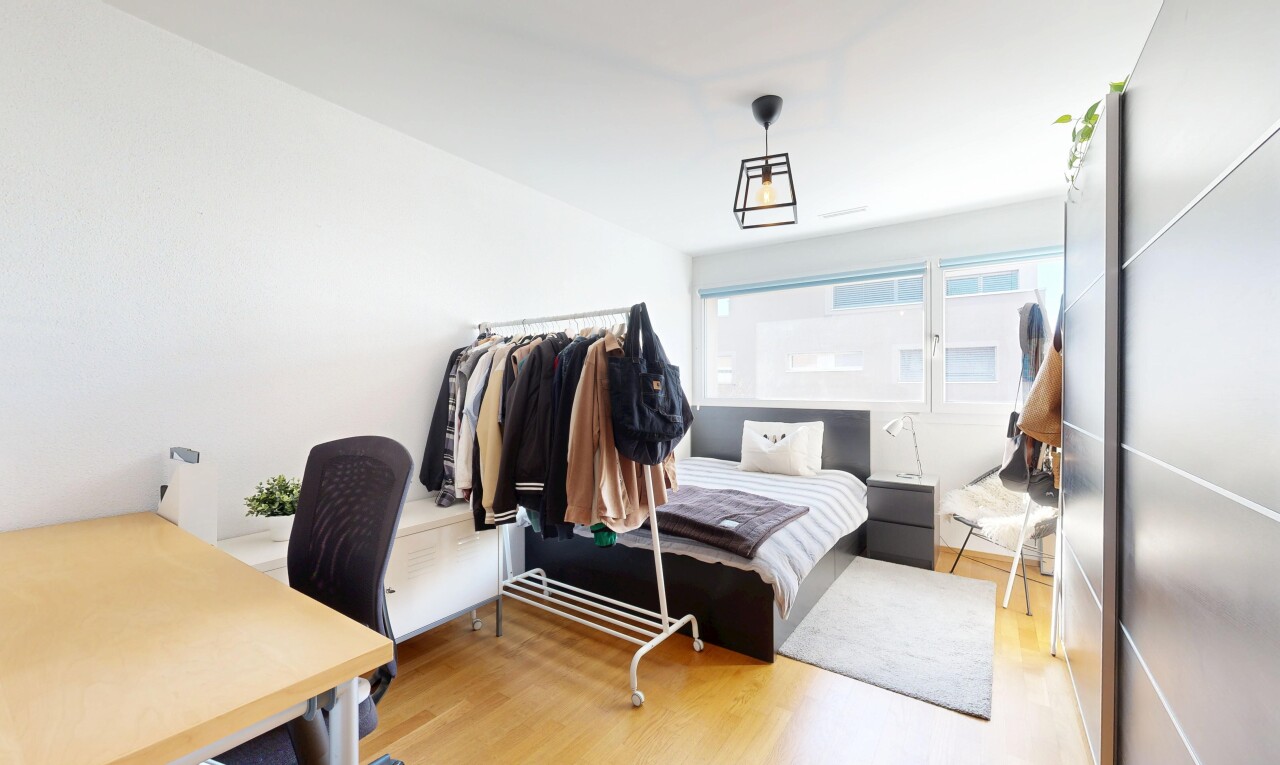 chambre avec espace bureau, wood finish floor, sol en finition bois, inside property, et natural light