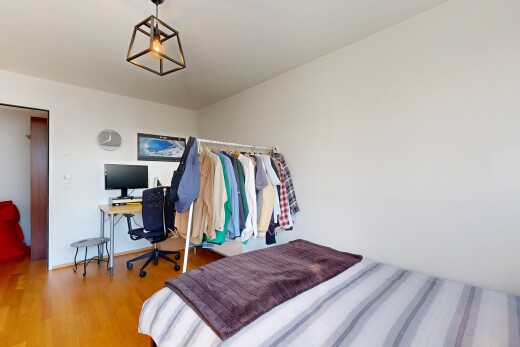chambre avec espace bureau, drywall, cloison sèche, télévision, et wood finish floor