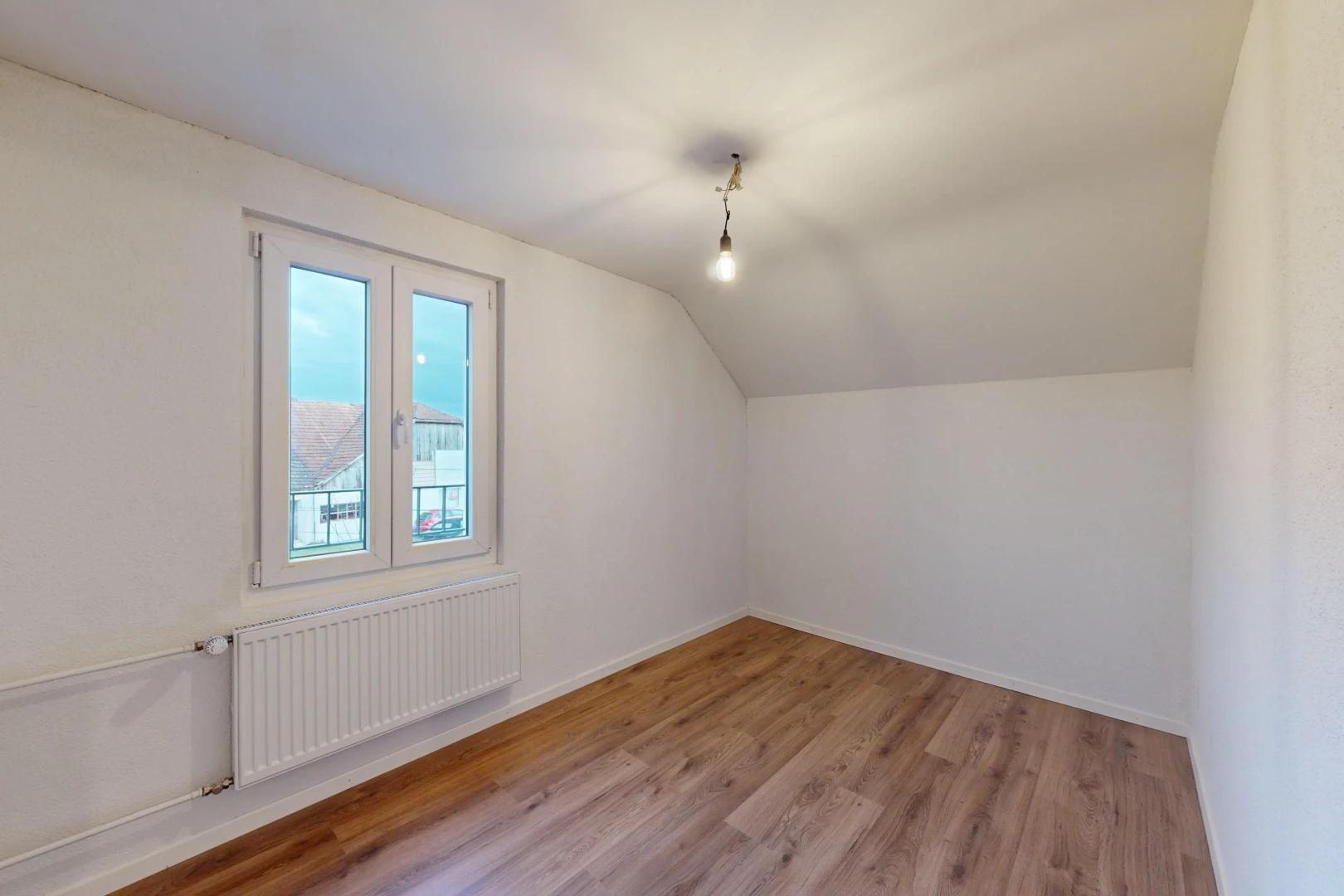 pièce vide avec lumière naturelle, radiateur, plafond bas, plancher de bois, et plafond voûté