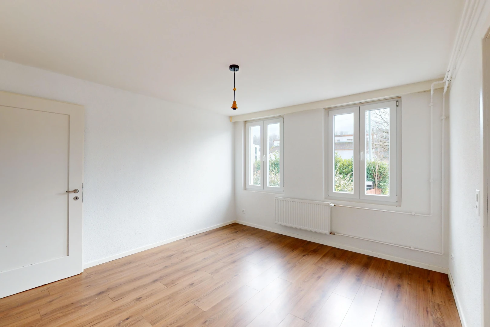 pièce vide avec plancher de bois, radiateur, et lumière naturelle