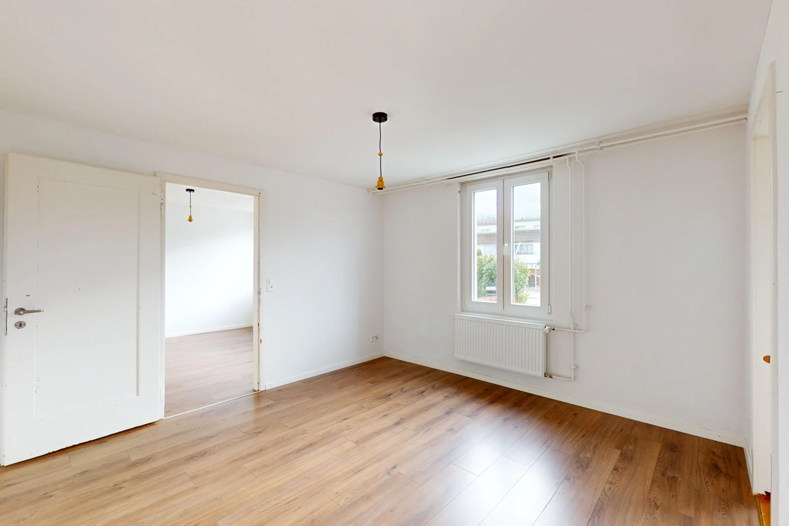 pièce vide avec radiateur, lumière naturelle, et plancher de bois