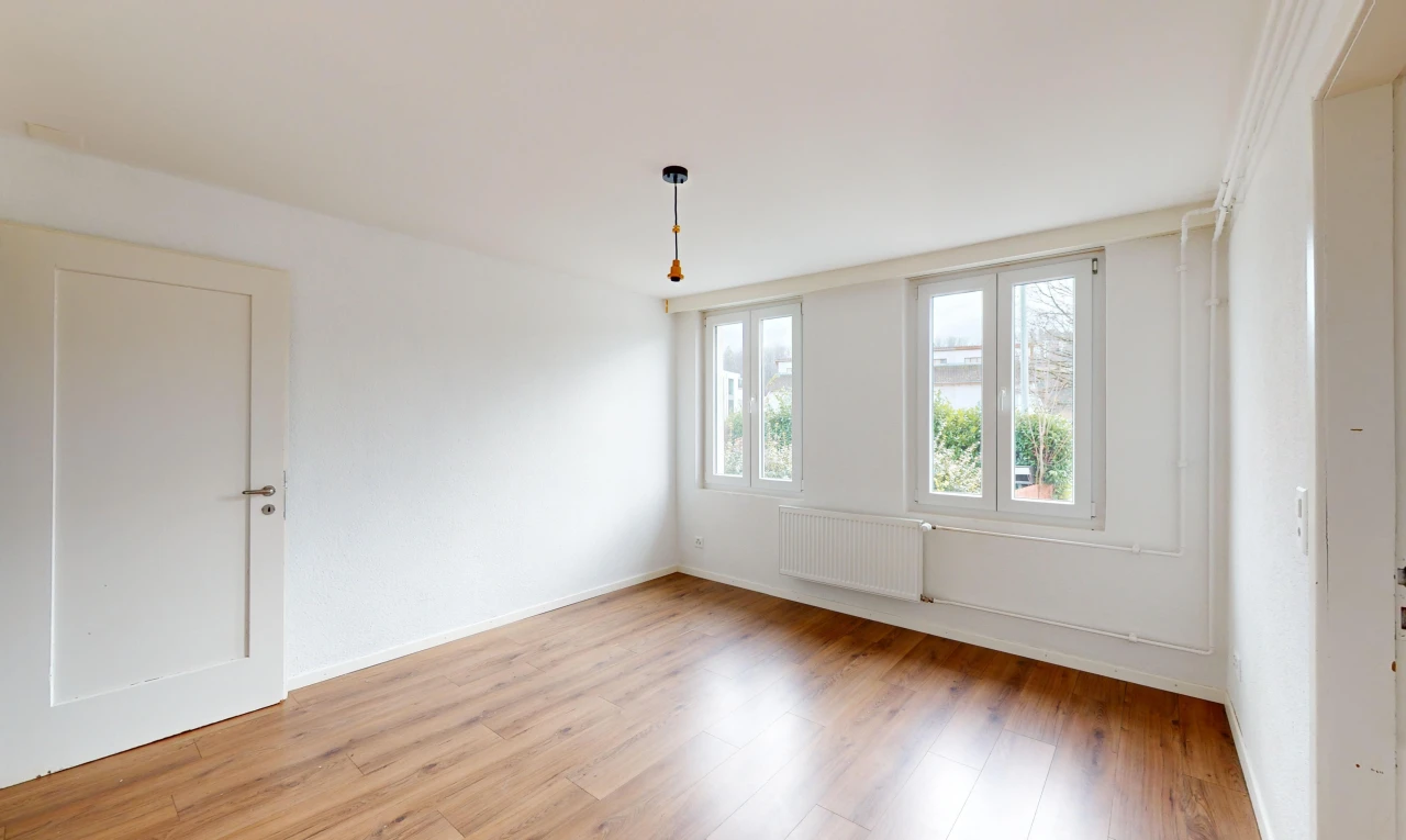 pièce vide avec plancher de bois, radiateur, et lumière naturelle