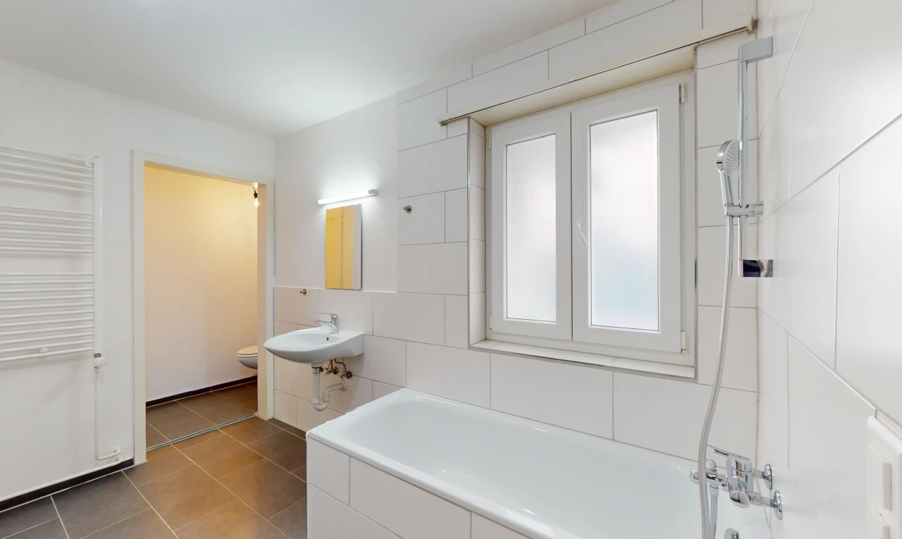 salle de bains avec lumière naturelle, miroir, carrelage, toilettes, et baignoire