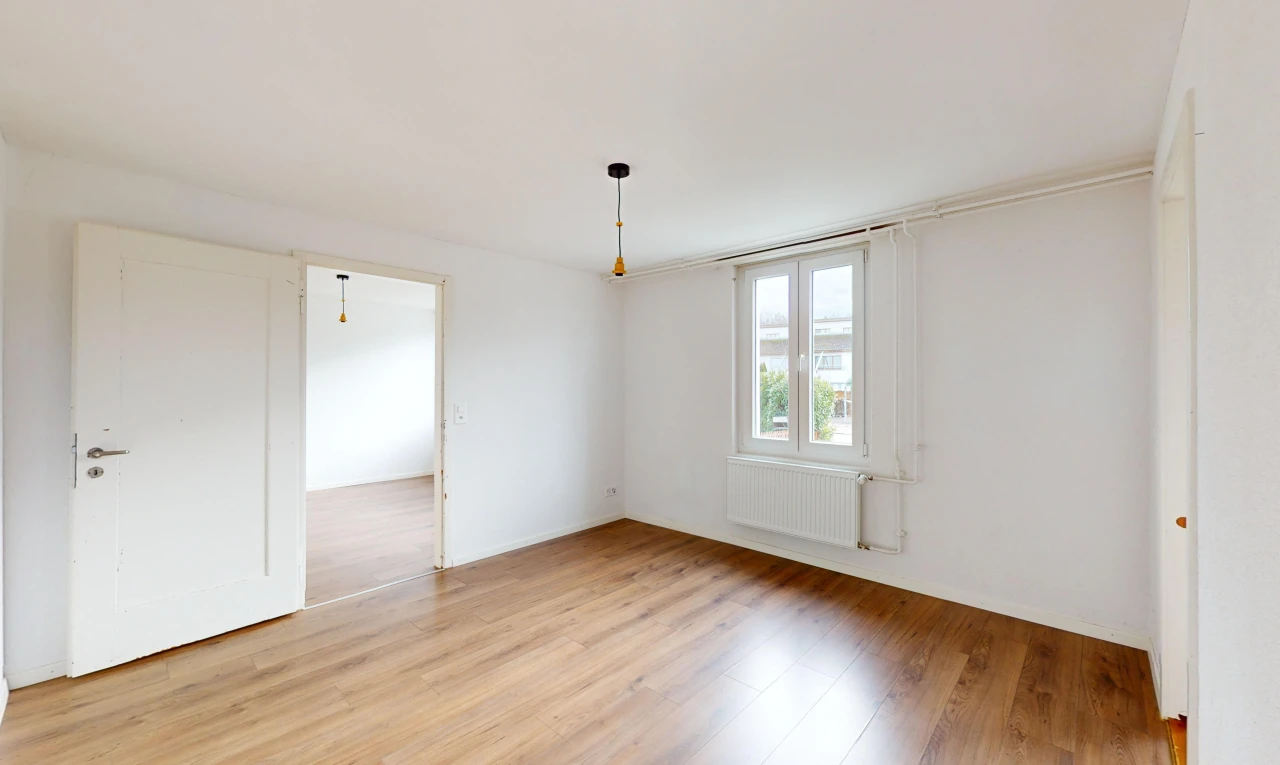 pièce vide avec radiateur, lumière naturelle, et plancher de bois