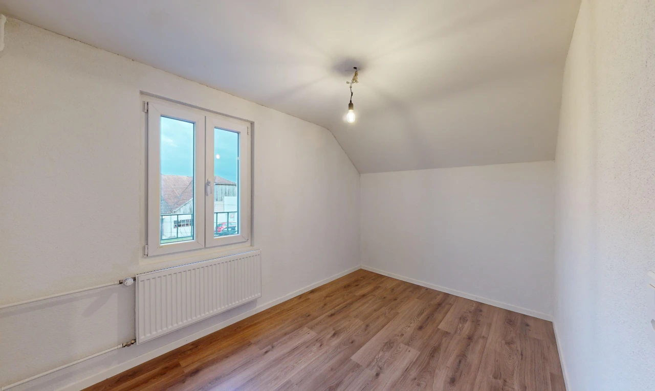 pièce vide avec lumière naturelle, radiateur, plafond bas, plancher de bois, et plafond voûté