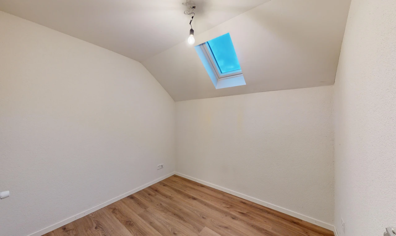 pièce vide avec lumière naturelle, plancher de bois, lucarne, et plafond voûté