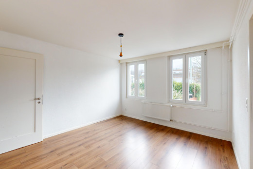 pièce vide avec plancher de bois, radiateur, et lumière naturelle