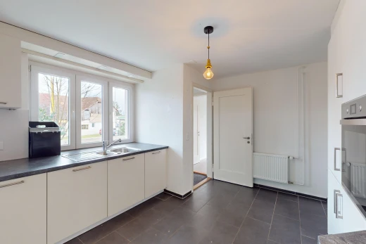 kitchen with pendant lighting, sink, white cabinetry, dark tile patterned floors, and radiator heating unit