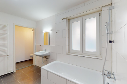 salle de bains avec lumière naturelle, miroir, carrelage, toilettes, et baignoire