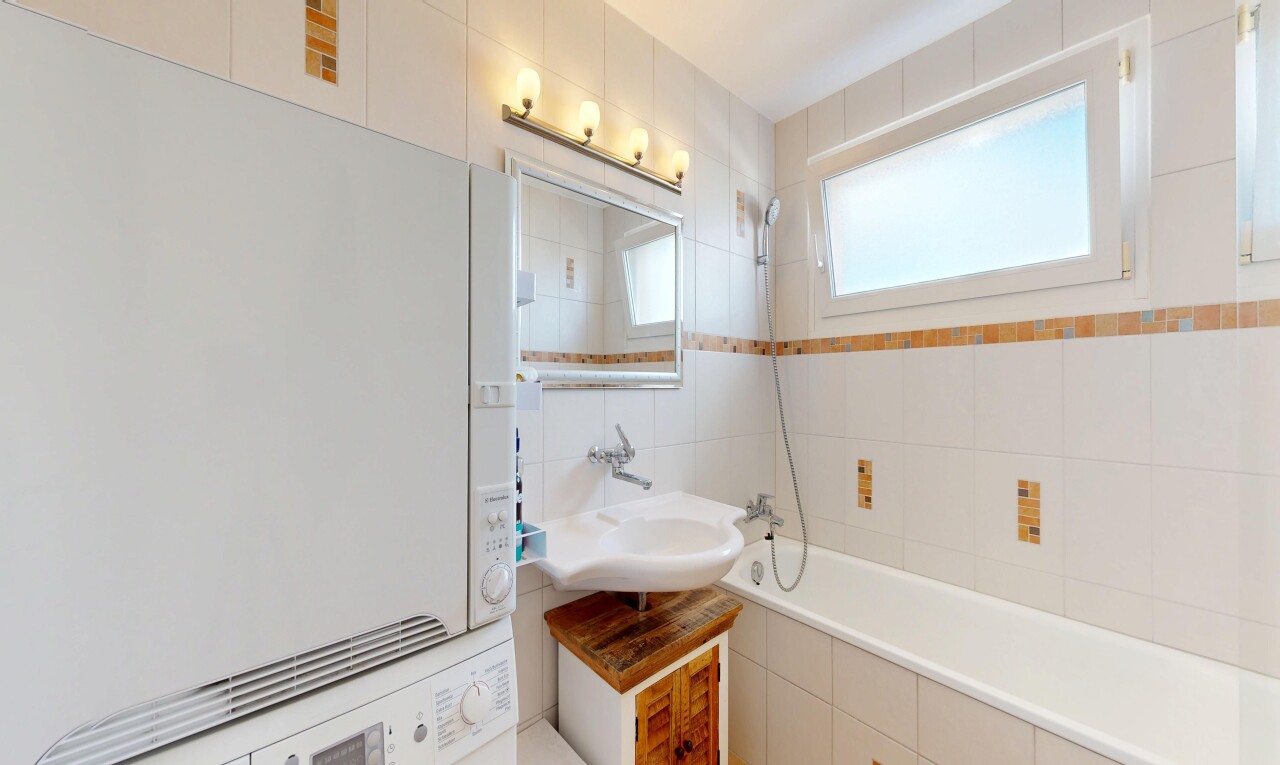bathroom with washer / dryer, tiled shower / bath, and tile walls