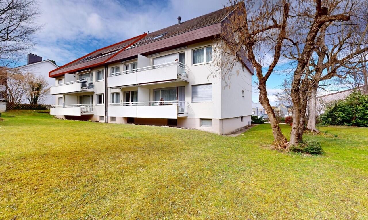 view of property with a yard, stucco siding, and a balcony
