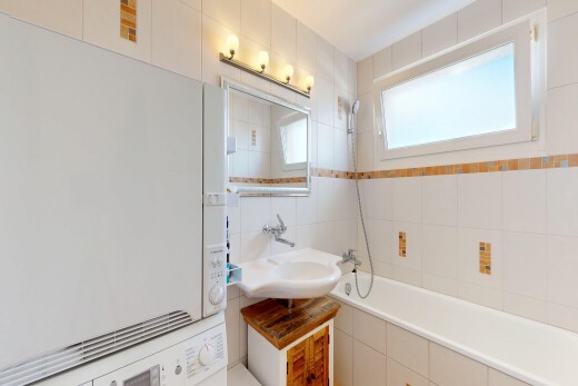 bathroom with washer / dryer, tiled shower / bath, and tile walls