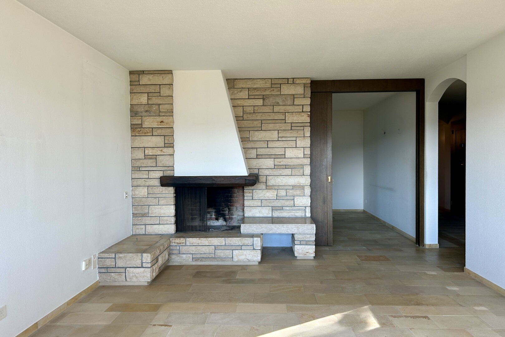pièce vide avec passages en arc, cloison sèche, drywall, cheminée, et baseboards wall