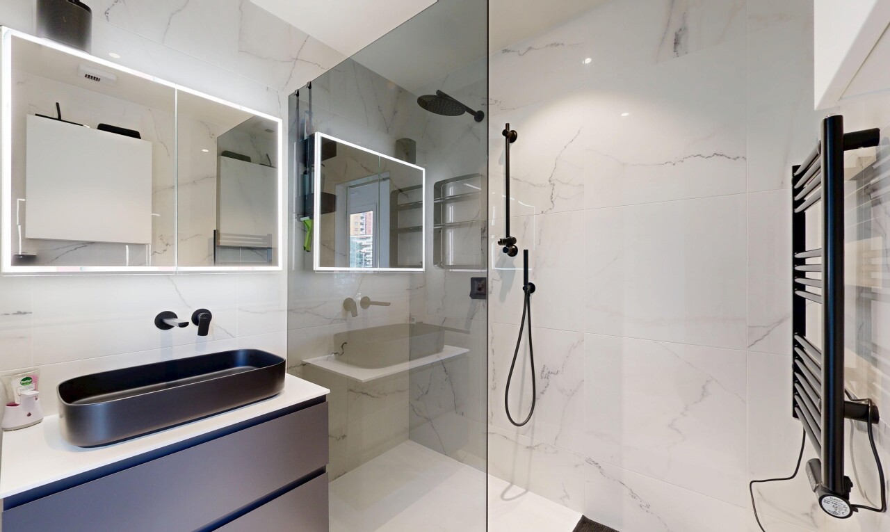 bathroom with a towel warmer, vanity, a marble finish shower, and radiator