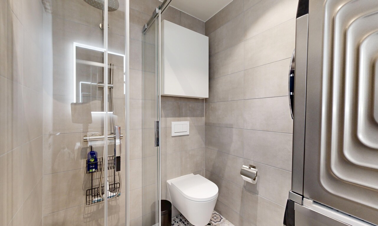 full bath featuring a stall shower, tile walls, and washer / clothes dryer
