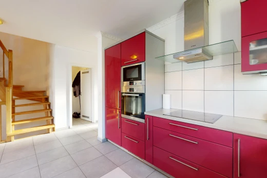 kitchen featuring stainless steel microwave, black electric stovetop, light tile patterned flooring, and wall chimney range hood