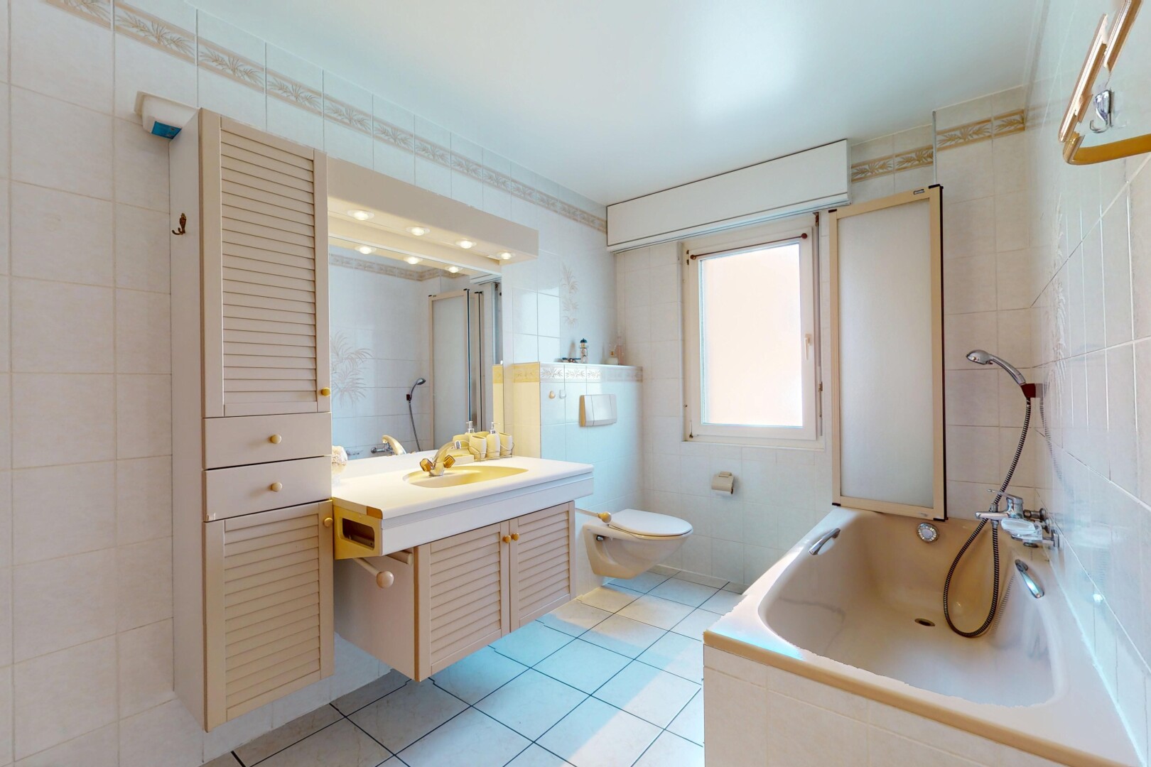 salle de bains avec toilette, bain, lumière naturelle, sol en carrelage, et évier
