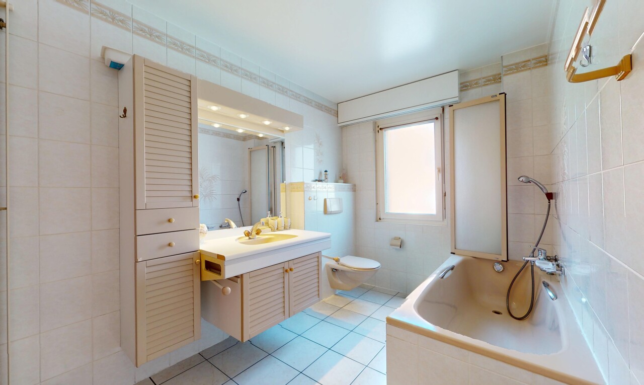 salle de bains avec toilette, bain, lumière naturelle, sol en carrelage, et évier
