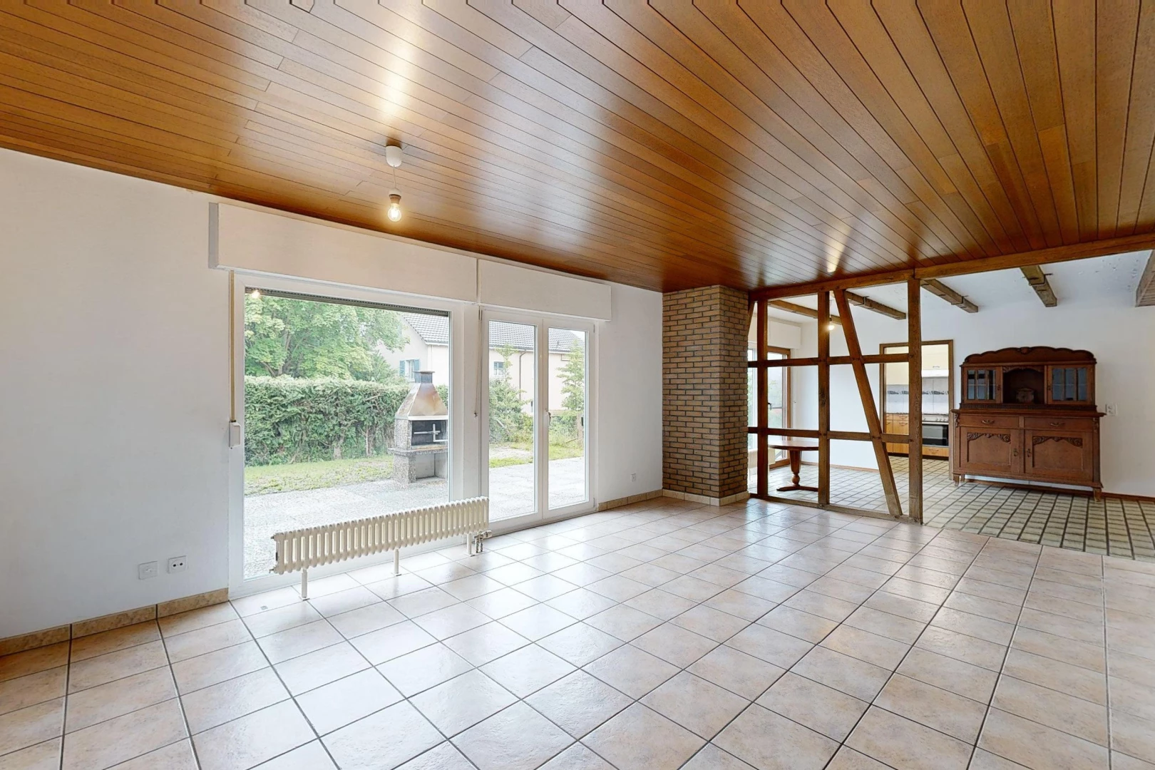 pièce vide avec carrelage, plafond de bois, mur en briques, et lumière naturelle
