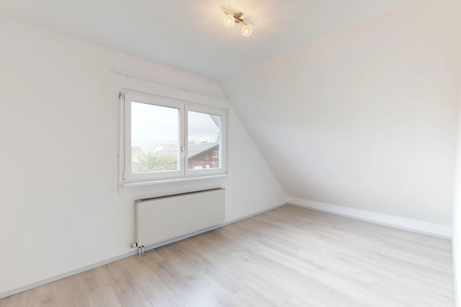 pièce vide avec plancher de bois, lumière naturelle, radiateur, plafond voûté, et plafond bas