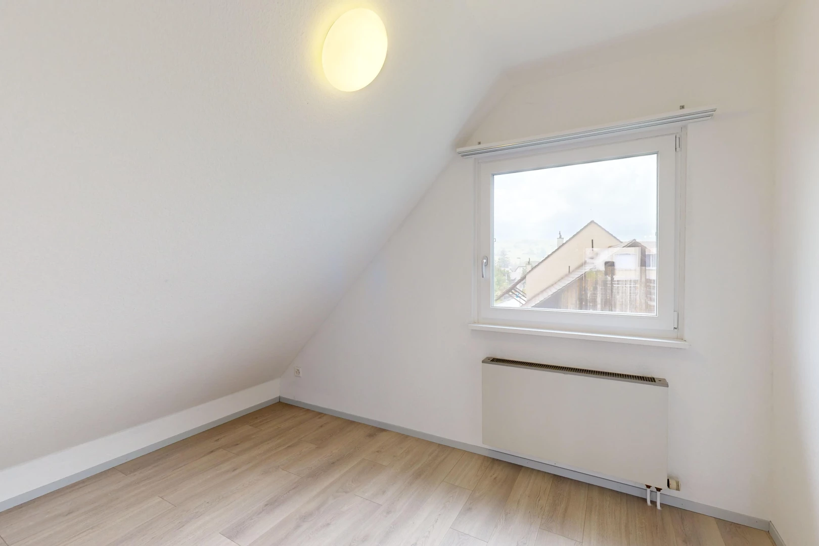 pièce vide avec plancher de bois, lumière naturelle, radiateur, plafond voûté, et plafond bas