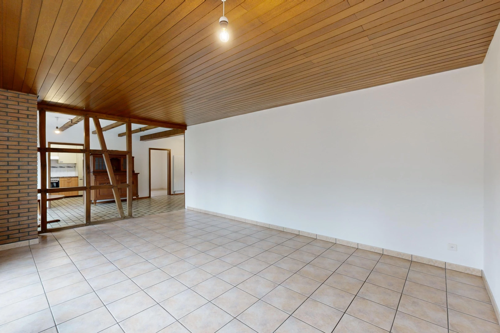 pièce vide avec plafond de bois, lumière naturelle, carrelage, et mur en briques