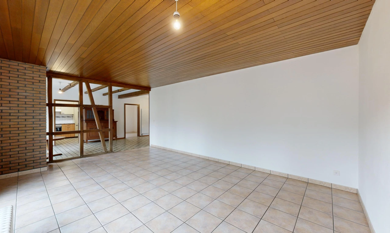 pièce vide avec plafond de bois, lumière naturelle, carrelage, et mur en briques