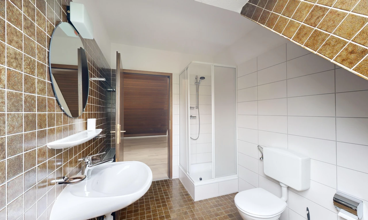salle de bain avec mur carrelé, douche, et miroir